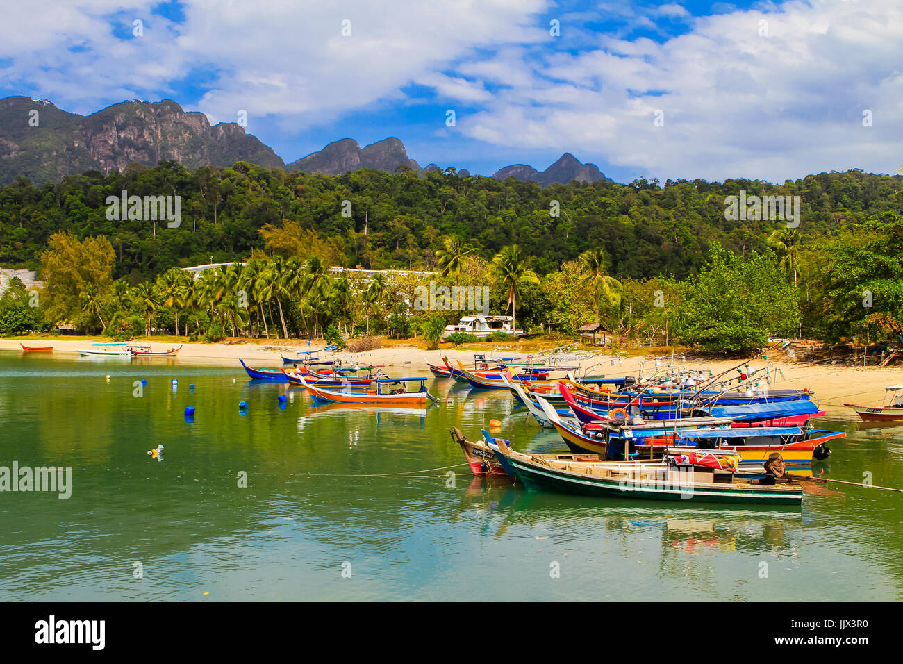 Traditional asian fishing boats anchored near fisherman houses in bay. Langkawi, Malaysia. Stock Photo