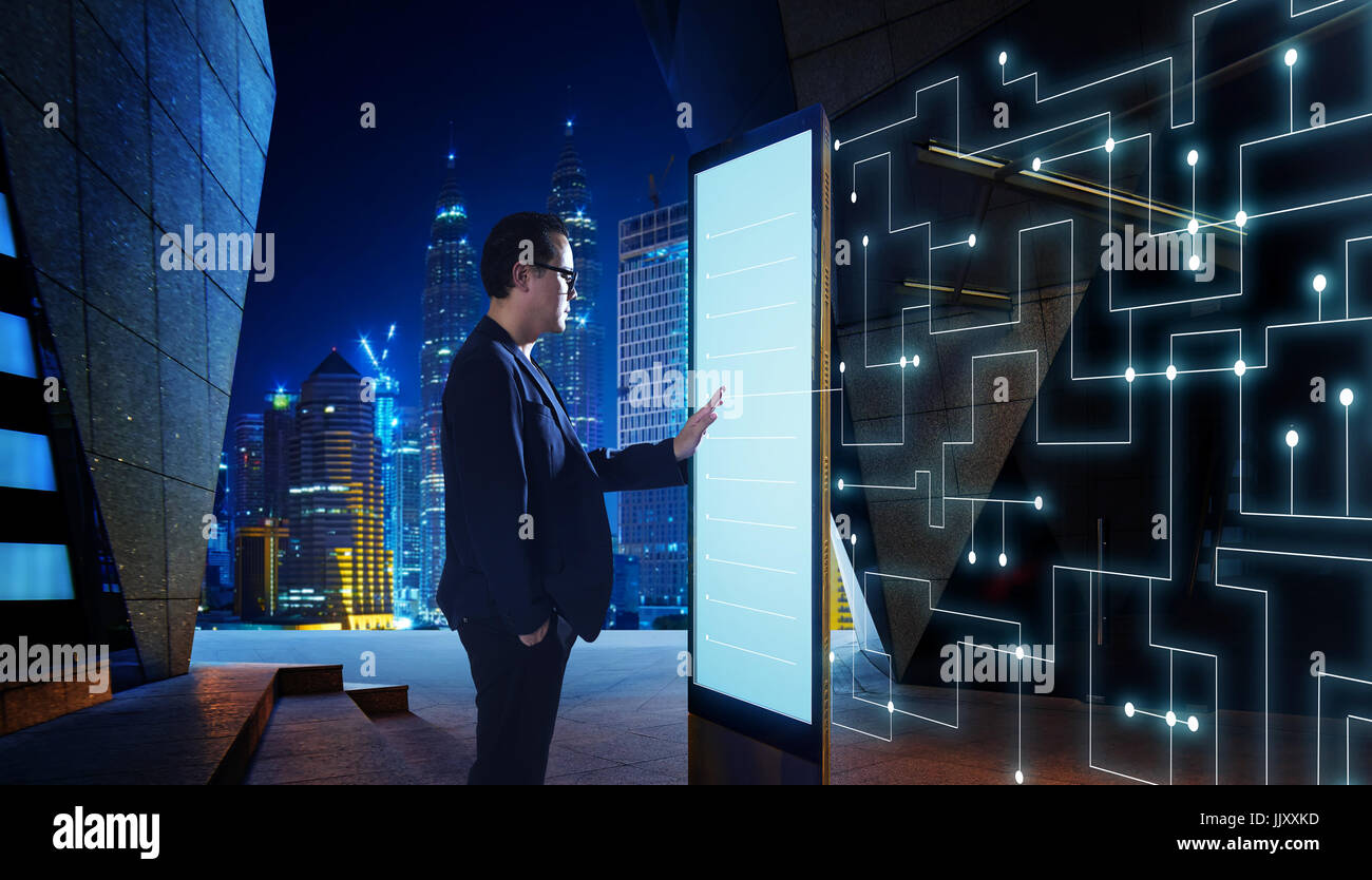 Smart businessman touch the screen to search the information of intelligent communication network of things . Night scene with modern city background  Stock Photo