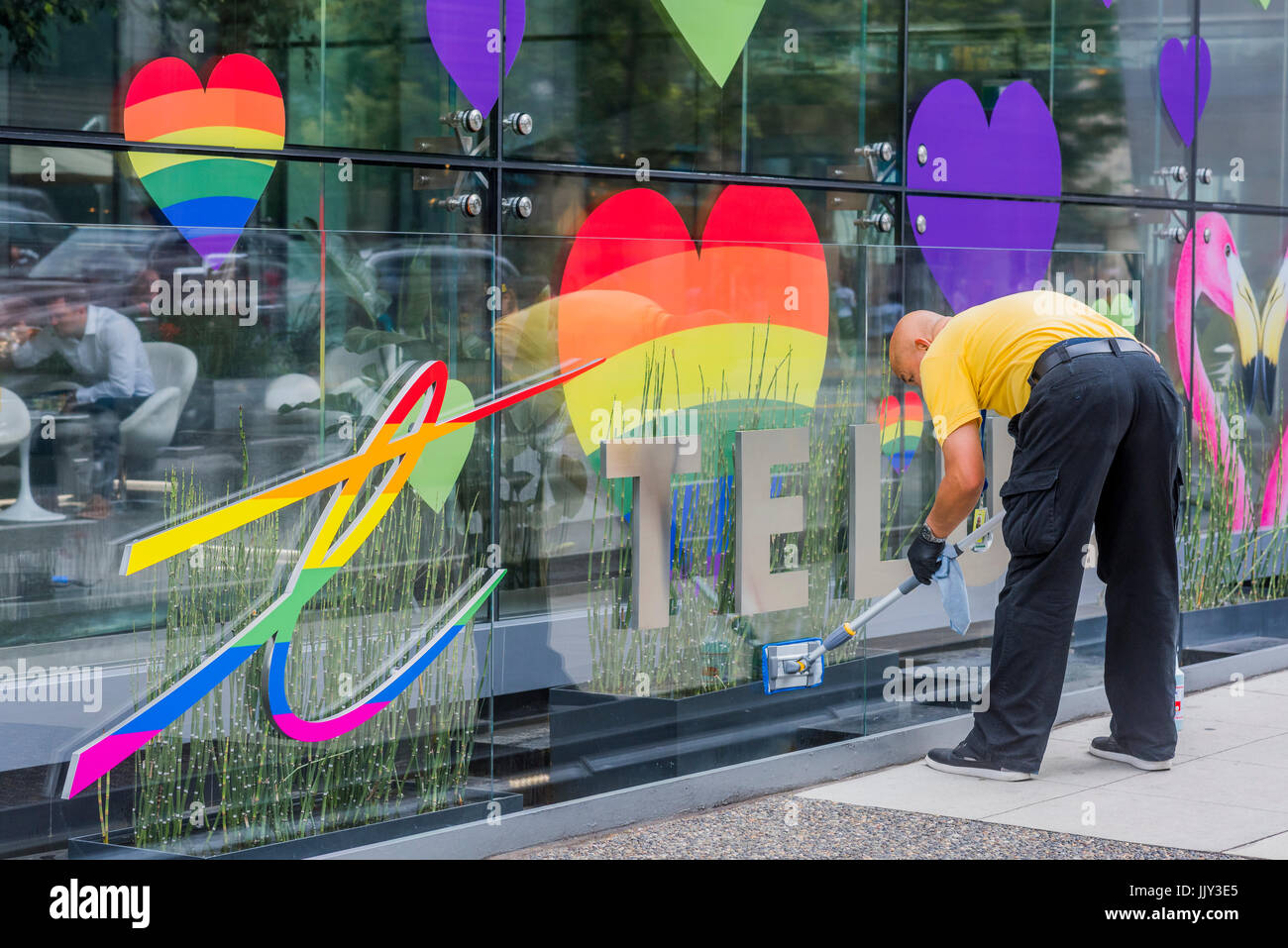 Window cleaner and Gay Pride rainbow hearts display.. Telus Garden