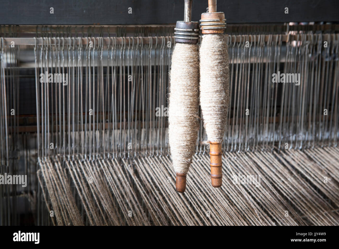 Vintage wool textile loom with wooden bobbins inside materials factory