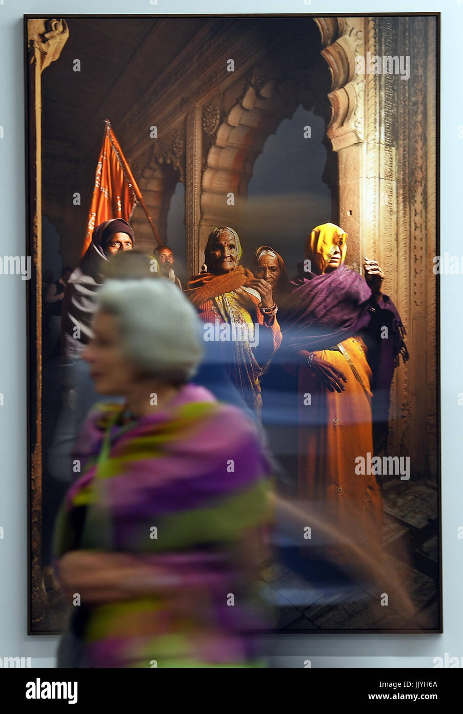 A woman walking in front of a photograph by Andre Wagner during the sneak preview of the exhibition 'Reflections of India' in the Moritzburg art museum in Halle/Saale, Germany, 21 July 2017. The show brings together photo works by American photographer Manjari Sharma and German photographers Andre Wagner and Manfred Paul. The exhibition shows an India full of contrasts with a culture thousands of years old portrayed in modern photography. 'Reflections of India' will open on 24 July and will last until 15 October 2017. Photo: Hendrik Schmidt/dpa-Zentralbild/dpa Stock Photo