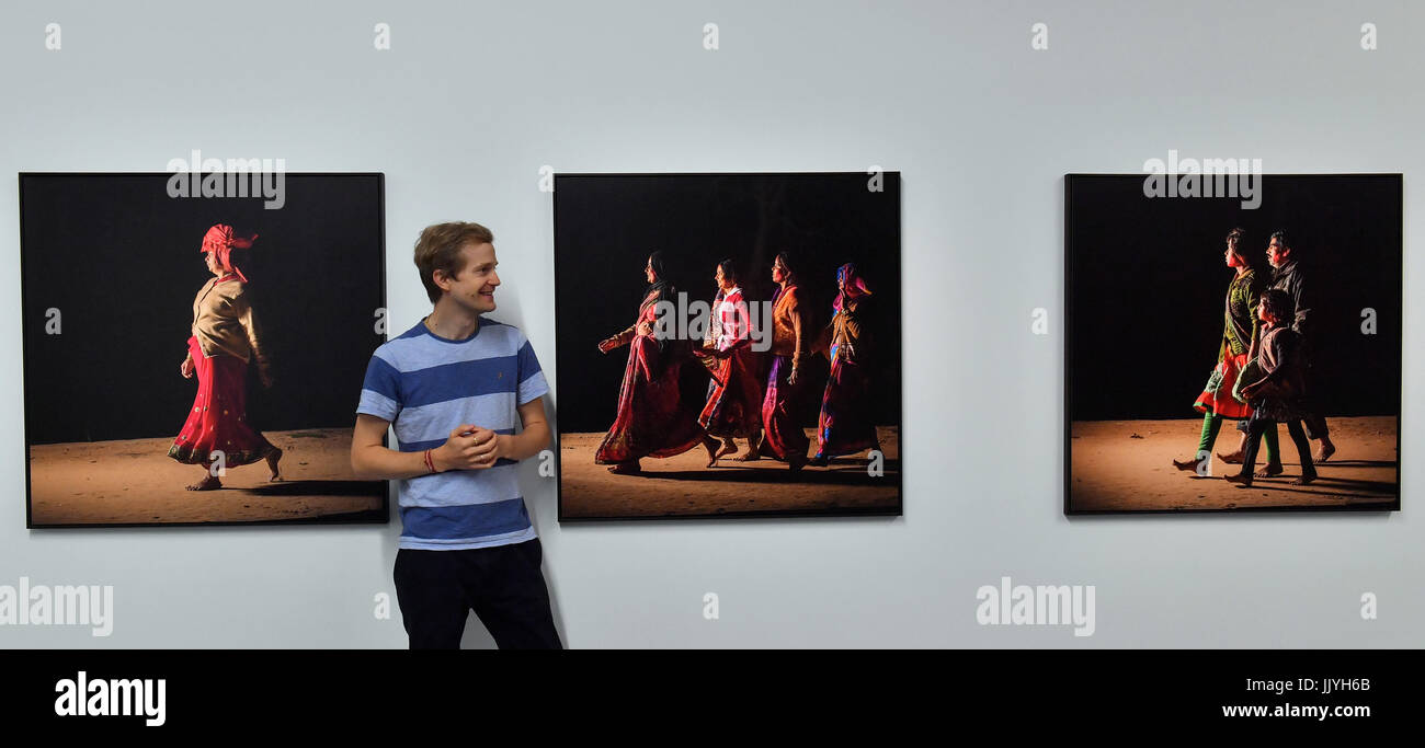 Photographer Andre Wagner standing between photos of his series with pilgrims at the exhibition 'Reflections of India' in the Moritzburg art museum in Halle/Saale, Germany, 21 July 2017. The show brings together photo works by American photographer Manjari Sharma and German photographers Andre Wagner and Manfred Paul. The exhibition shows an India full of contrasts with a culture thousands of years old portrayed in modern photography. 'Reflections of India' will open on 24 July and will last until 15 October 2017. Photo: Hendrik Schmidt/dpa-Zentralbild/dpa Stock Photo