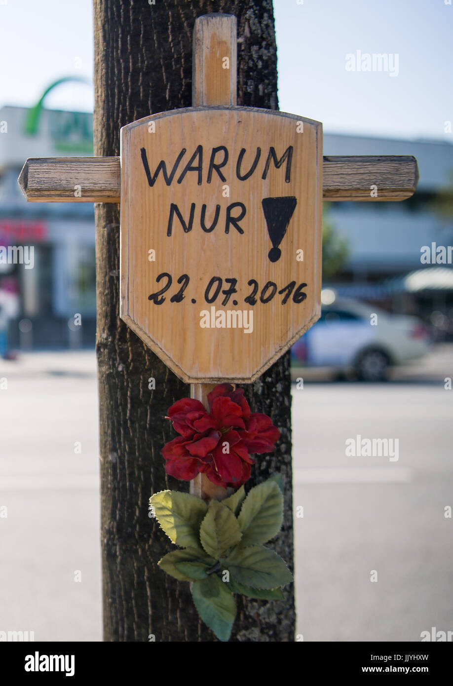 Munich, Germany. 21st July, 2017. A wooden cross with a sign with the inscription 'Just why! - 22.07-2016' hanging in front of the entrance to the Olympia shopping mall in Munich, Germany, 21 July 2017. On 22 July 2016 the 18-year old student David S. shot 9 people and wounded others before taking his own life around the Olympia shopping mall in the Moosach district of Munich. Photo: Peter Kneffel/dpa/Alamy Live News Stock Photo