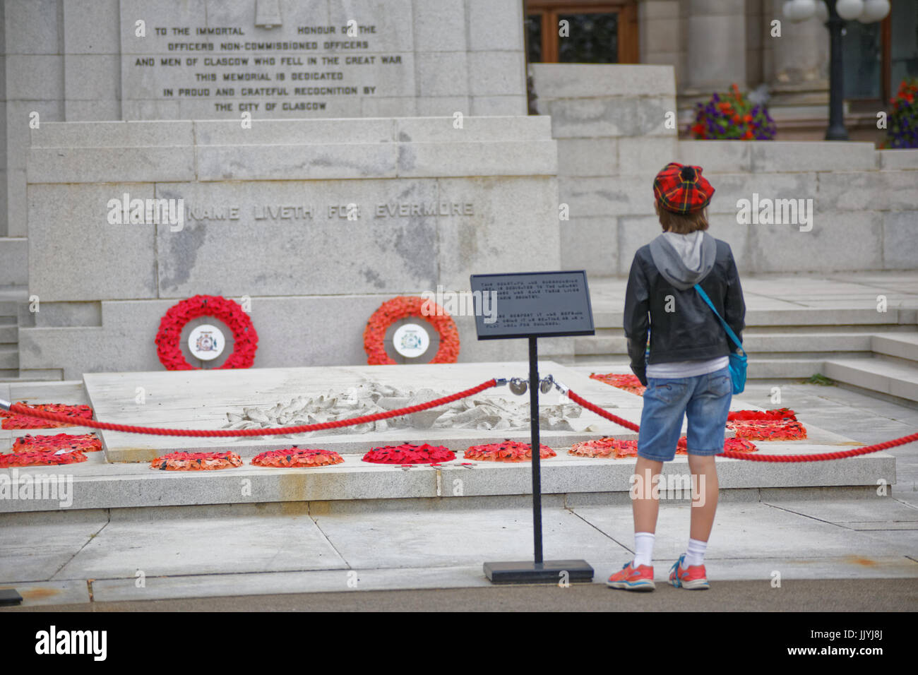 young teenage boy in tartan Tammy in front of the war memorial cenotaph George Square Glasgow red poppies Stock Photo
