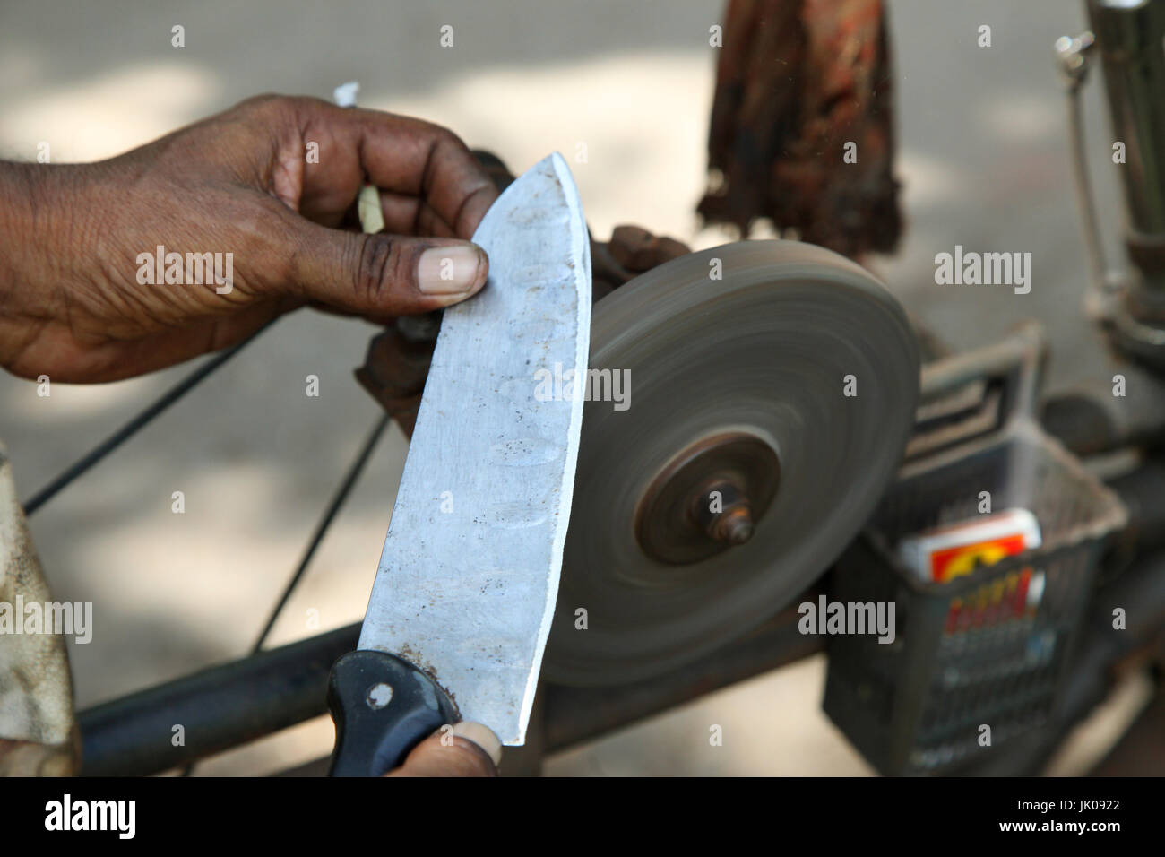 Sharpening knife on old grindstone wheel Stock Photo - Alamy