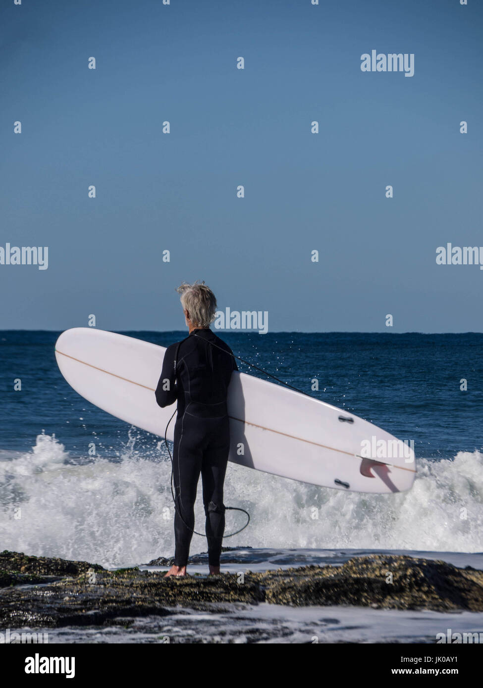 One Older Male Surfer standing and waiting for the Waves Shorebreak