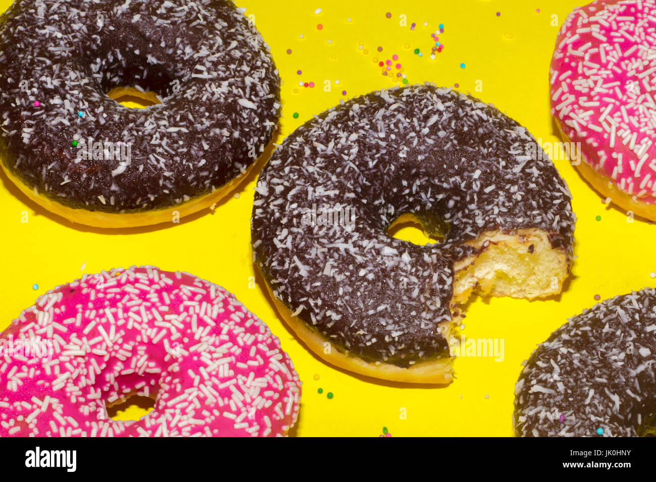 Strawberry and chocolate frosted donuts on yellow background Stock Photo