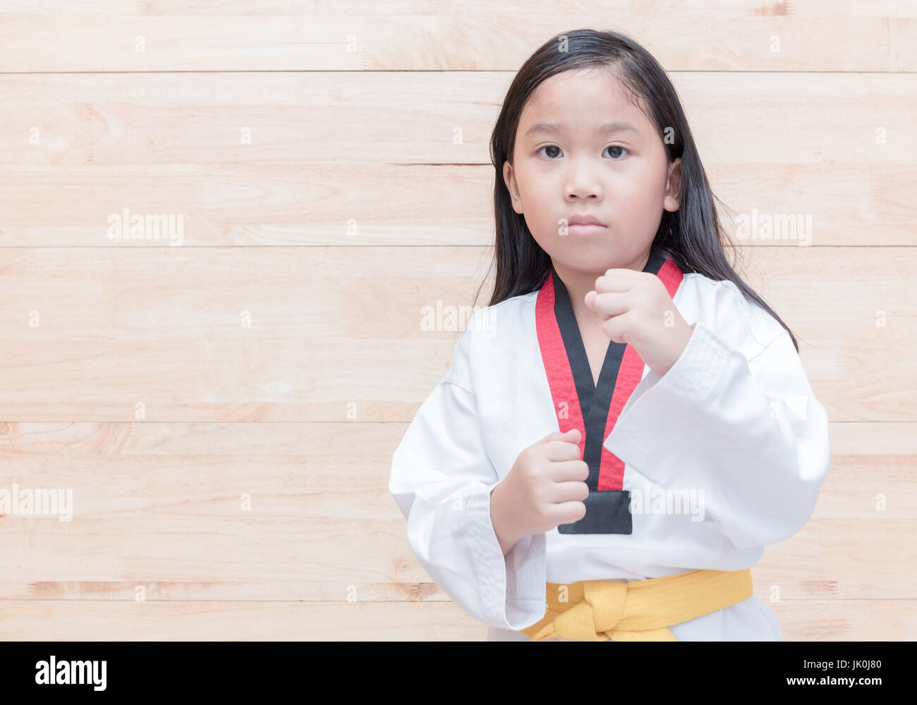 Asian taekwondo girl on acton on wood background, sport and healthy concept Stock Photo