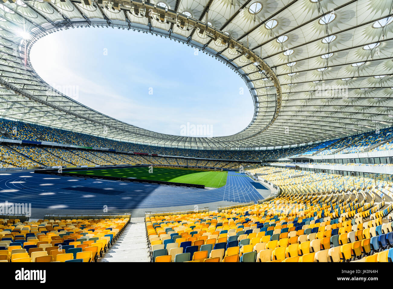 rows of yellow and blue stadium seats on soccer field stadium Stock Photo