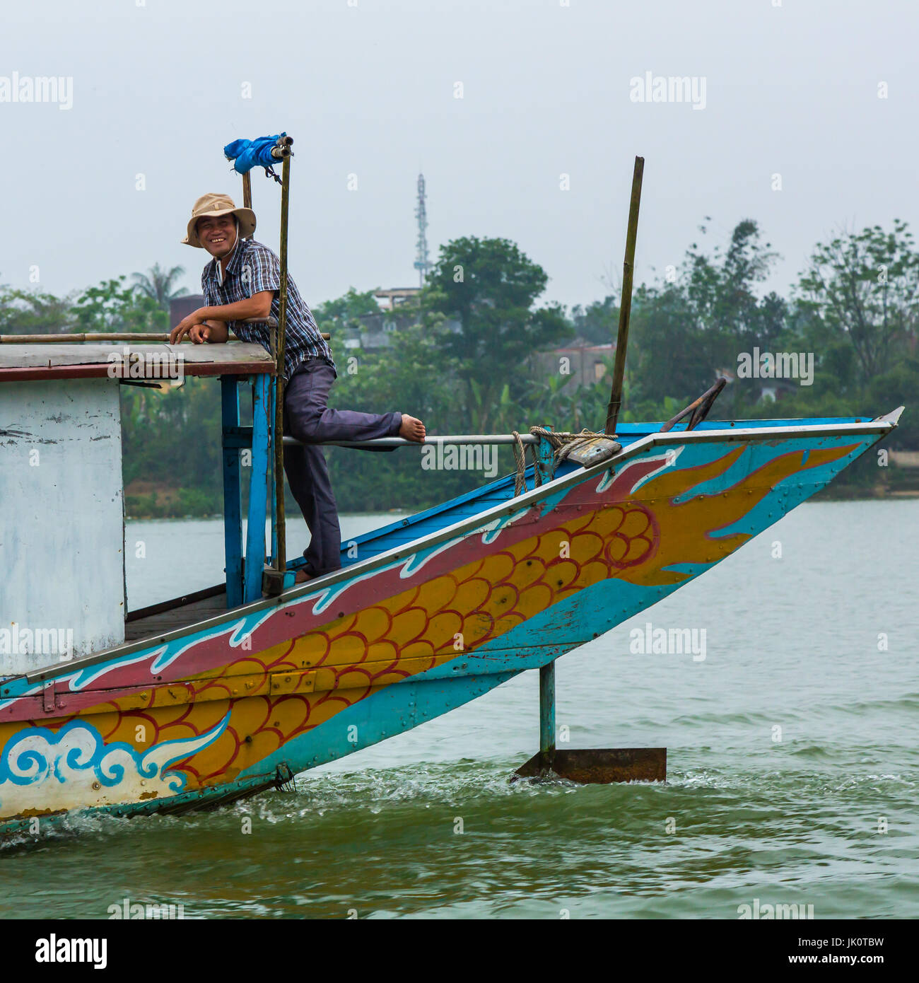 A local boat man beams as he casually steers his boat with his foot. Stock Photo