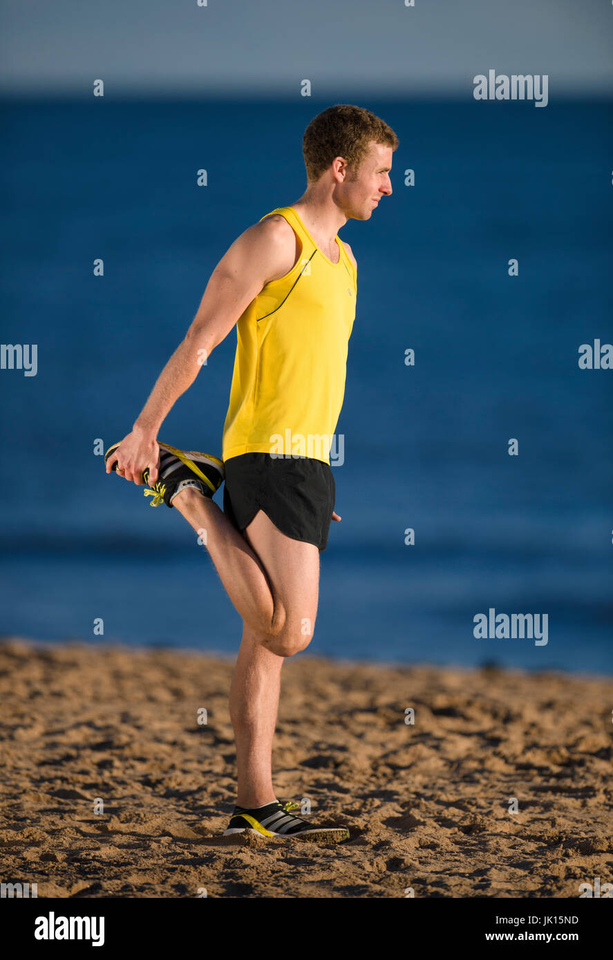 Runner warming up stretching quadriceps. Stock Photo