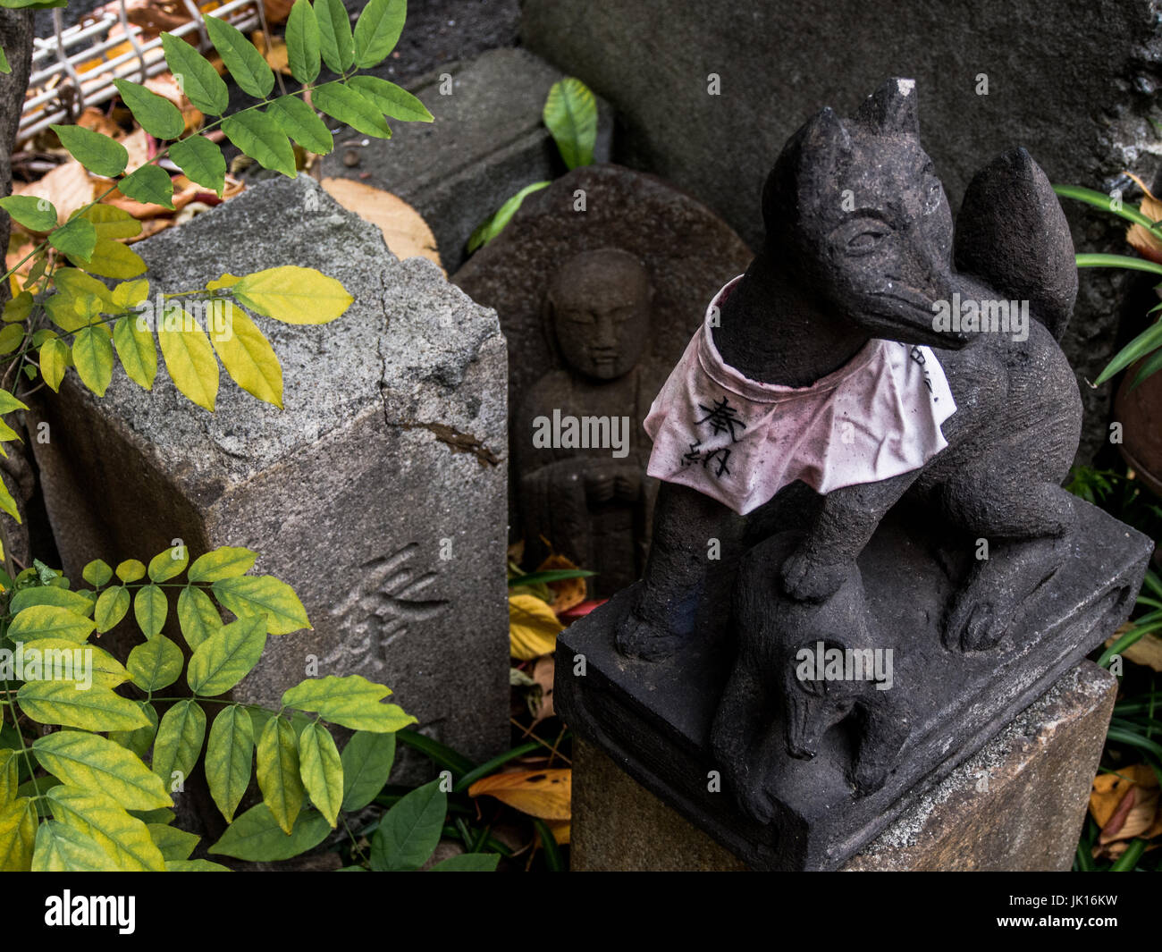 Sacred figurines, Kitsune fox guardian and buddhist statue, roadside shrine, Shinjuku, Tokyo, Japan Stock Photo