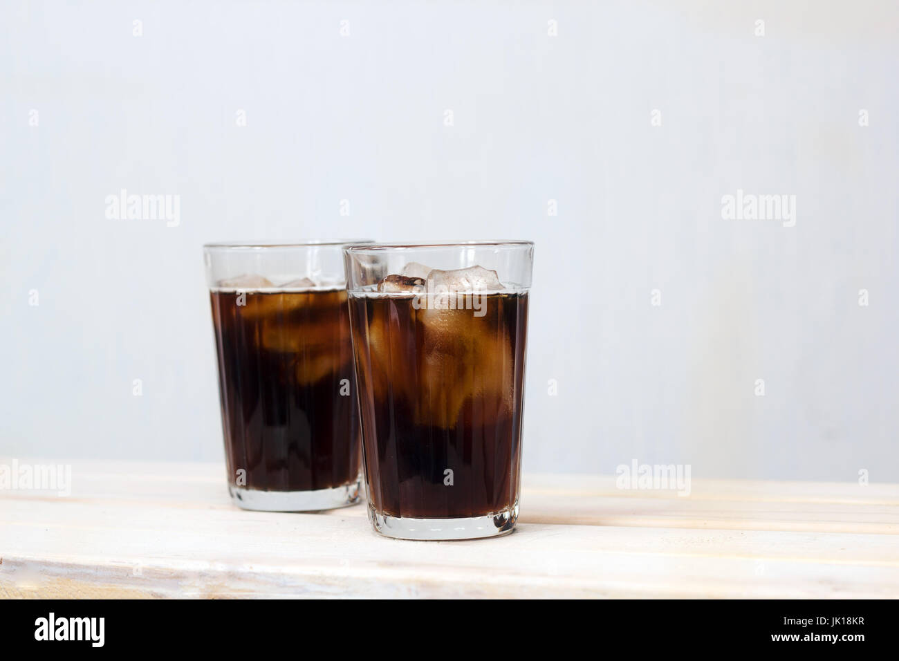 two glasses of black ice coffee  on a table against white wall Stock Photo