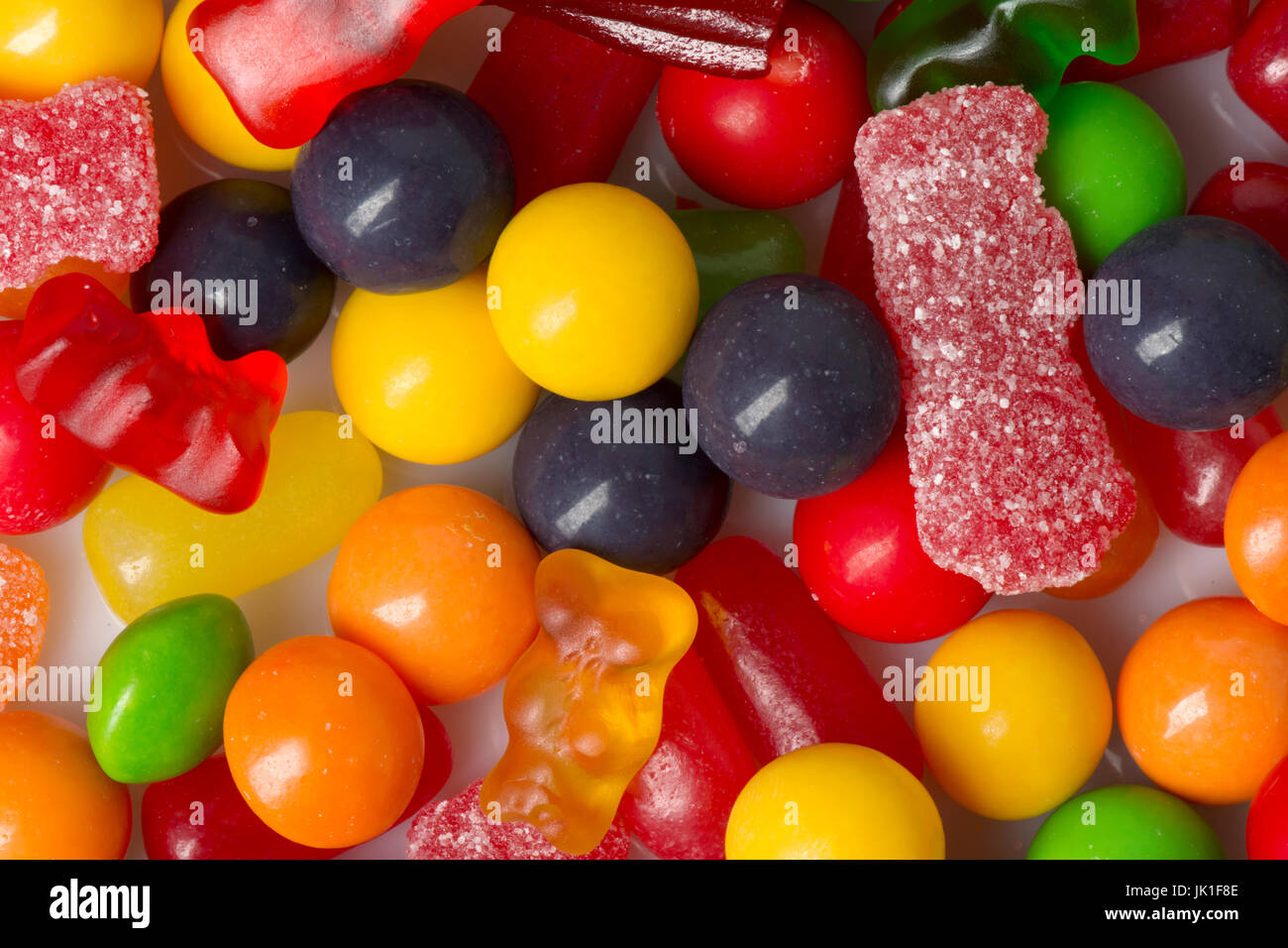 Closeup of various types of candy scattered on white Stock Photo Alamy