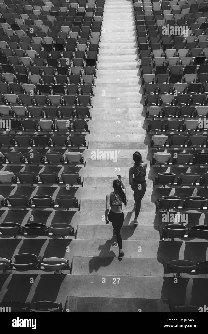 two sportswomen running on stadium stairs, black and white, running women concept Stock Photo