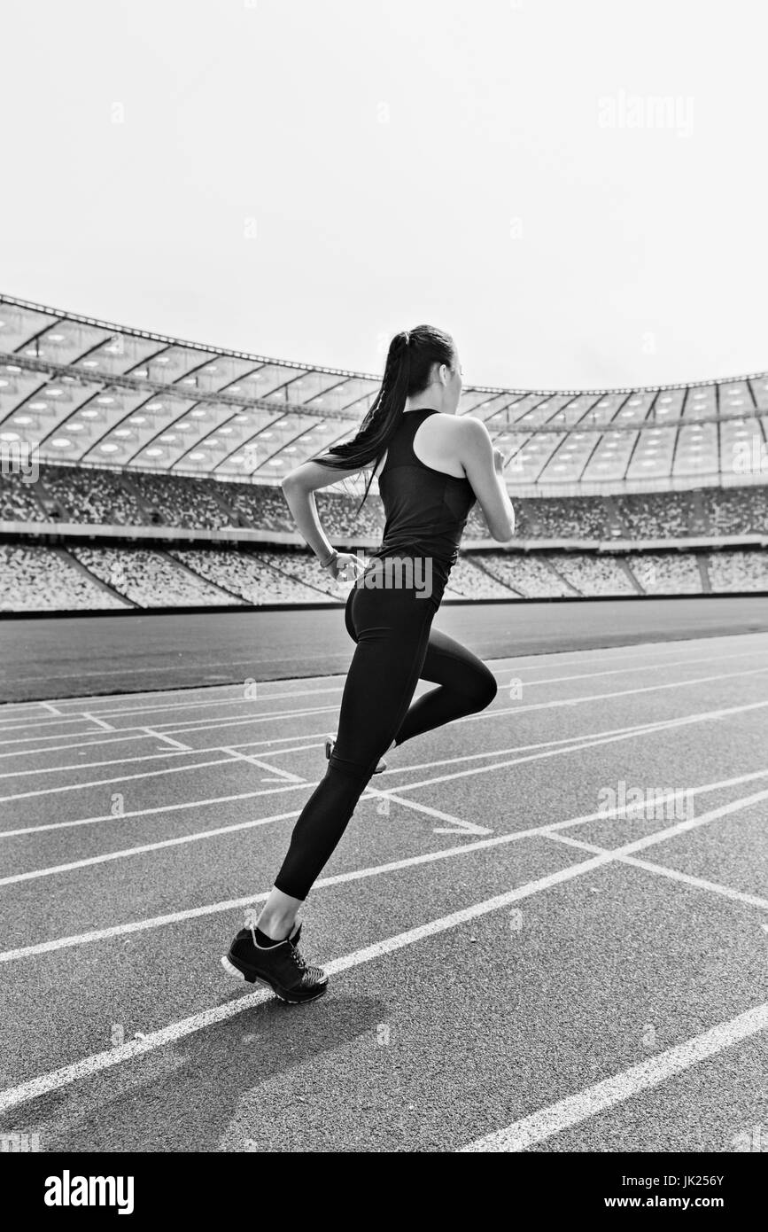 Young fitness woman in sportswear running on running track stadium, black and white photo Stock Photo
