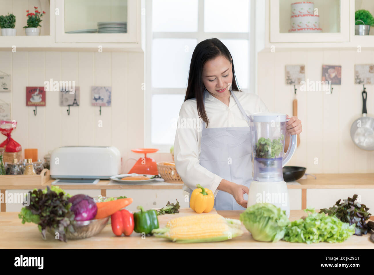 Vegetable smoothie. Asian woman making green smoothies with blender home in kitchen. Healthy raw eating lifestyle concept portrait of beautiful young  Stock Photo