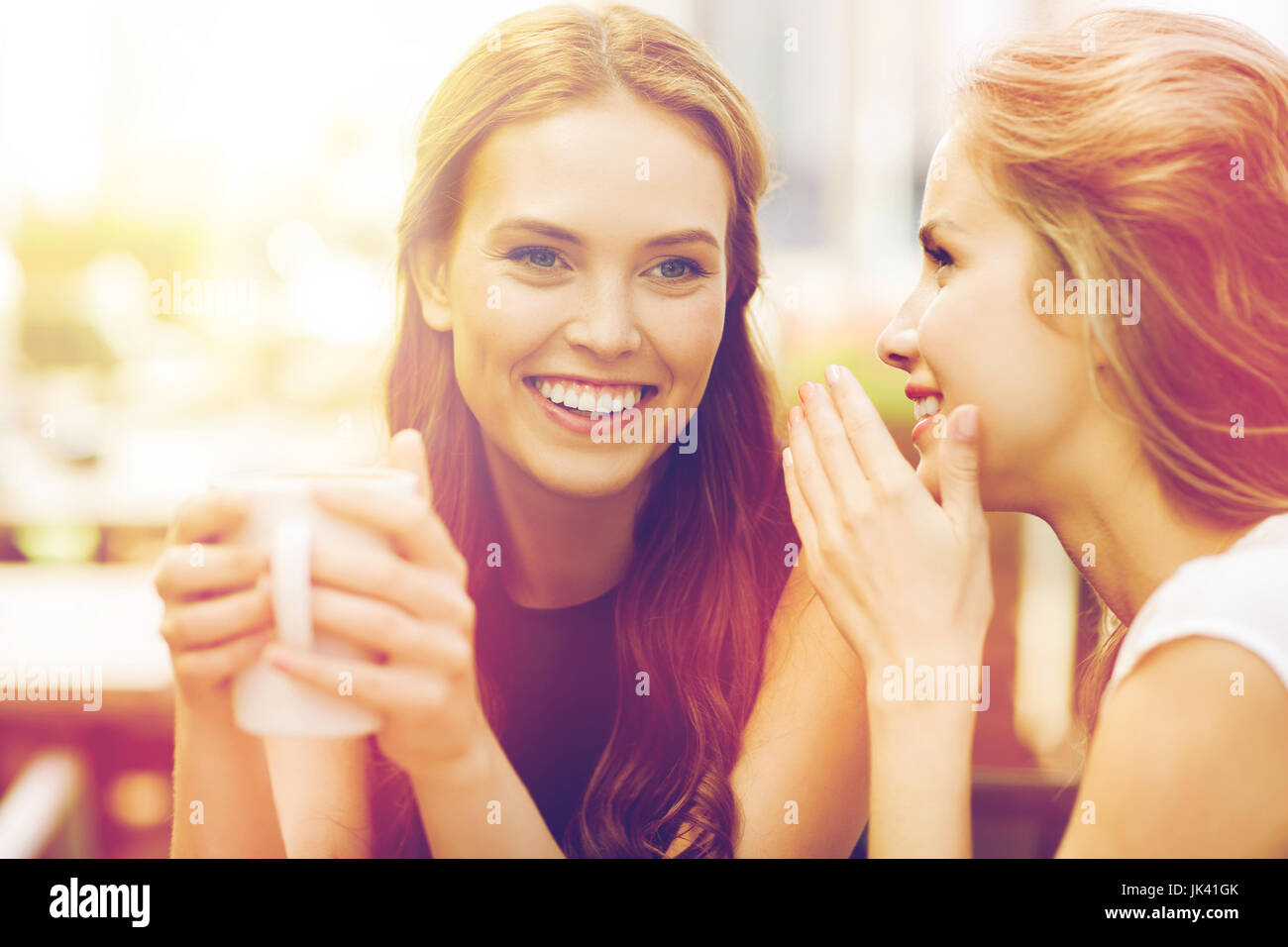 young women drinking coffee and talking at cafe Stock Photo