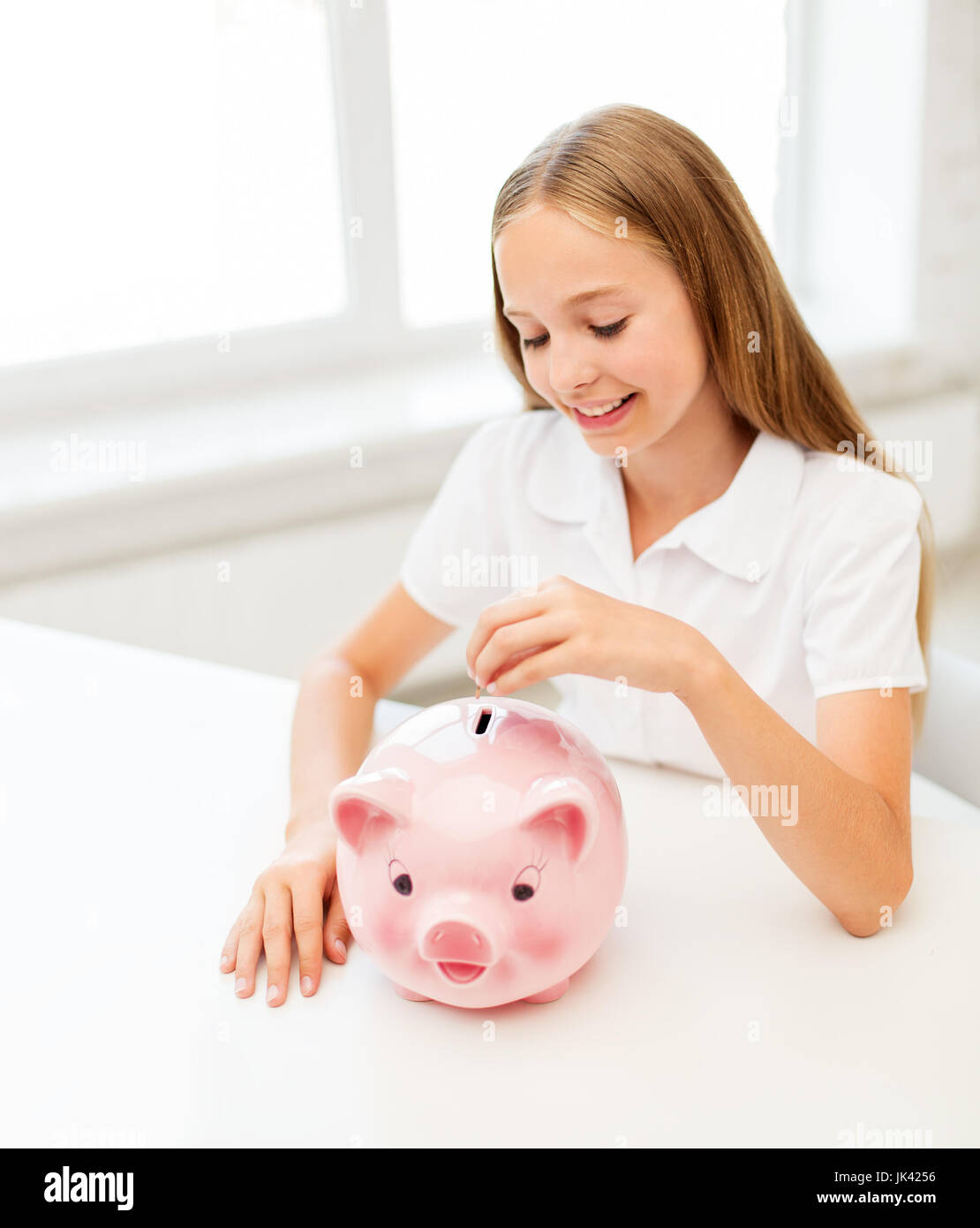 happy smiling girl putting coin into piggy bank Stock Photo - Alamy