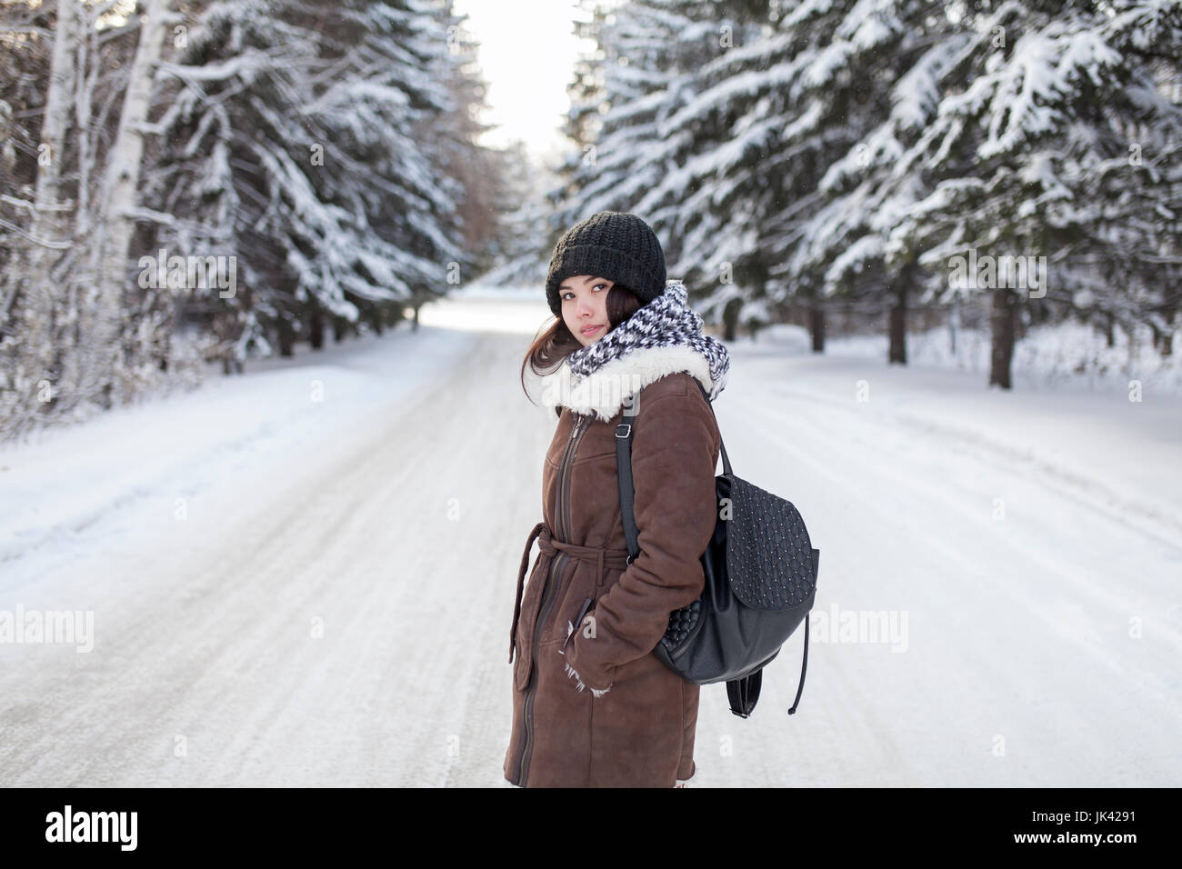 Asian woman carrying backpack on snowy road Stock Photo