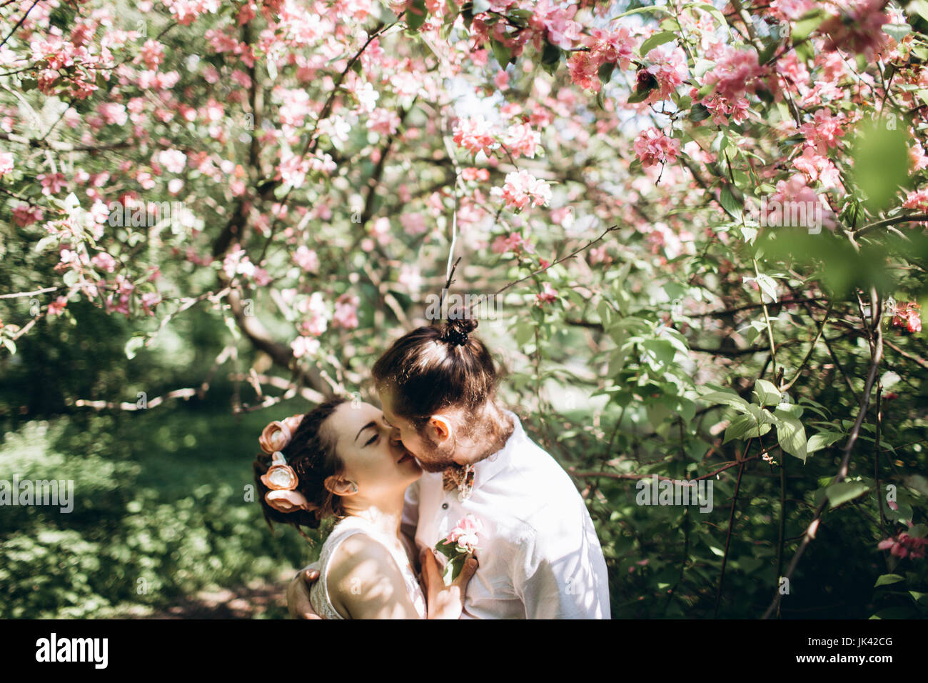 Middle Eastern couple kissing under flowering tree Stock Photo
