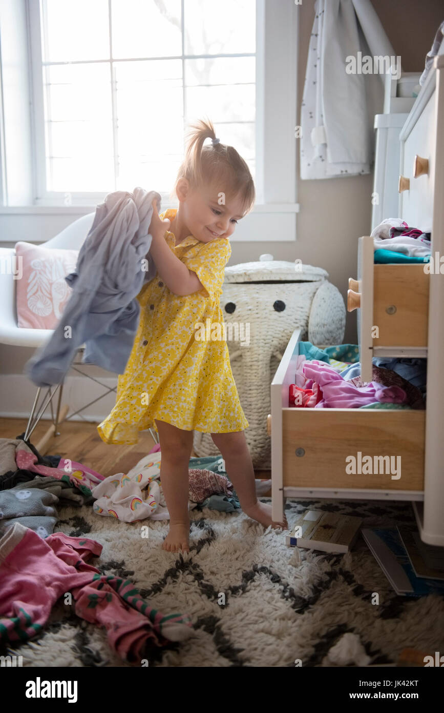 Caucasian baby girl removing clothing from dresser drawer Stock Photo