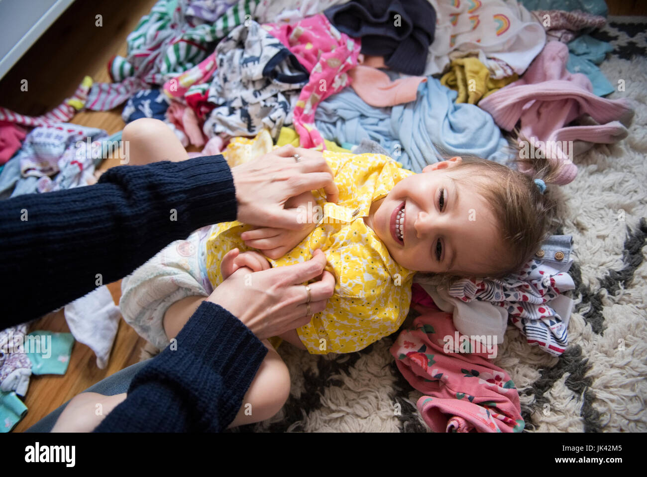 Hands of Caucasian mother tickling baby daughter on floor Stock Photo
