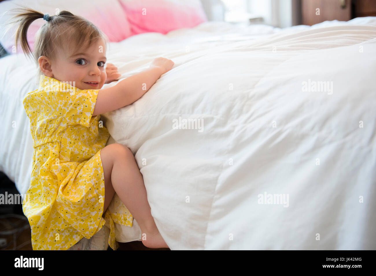 Caucasian baby girl climbing on bed Stock Photo Alamy