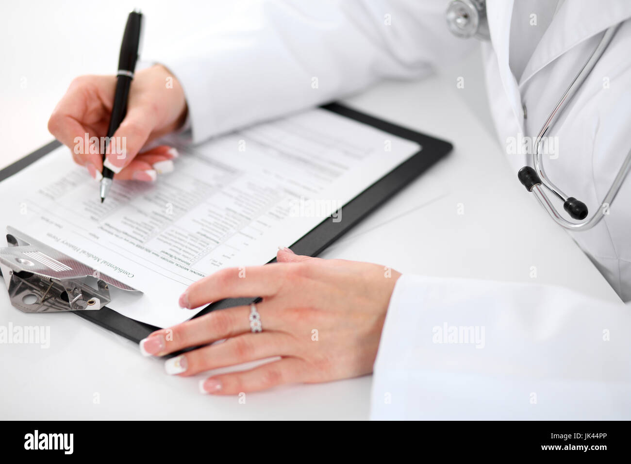Close-up of a female doctor filling out application form , sitting at ...