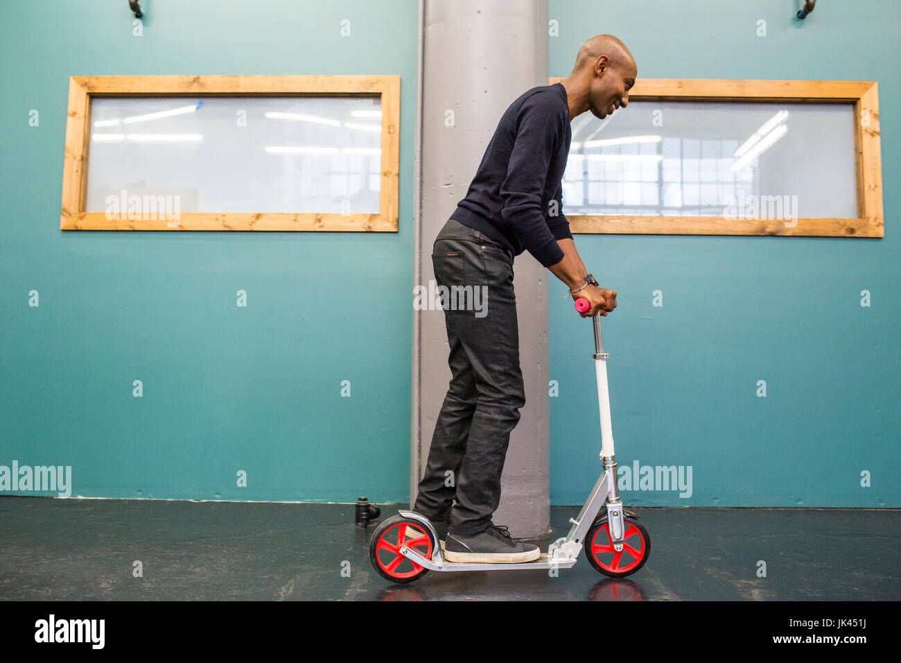 African American man riding scooter indoors Stock Photo