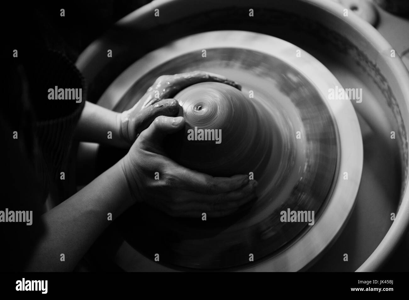 Hands of Caucasian woman shaping pottery clay on wheel Stock Photo