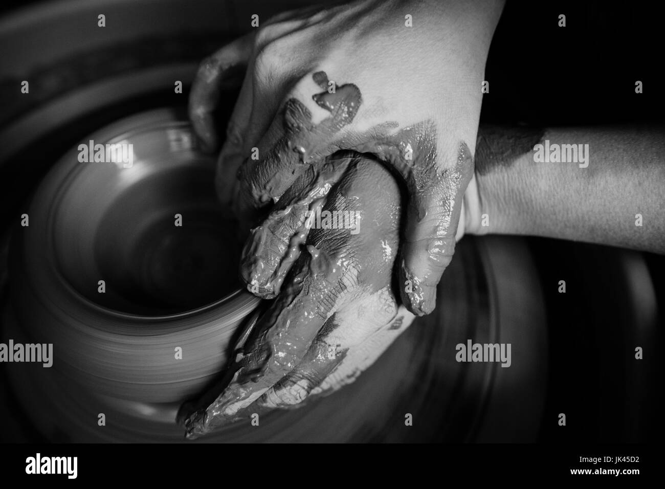 Hands of Caucasian woman shaping pottery clay on wheel Stock Photo