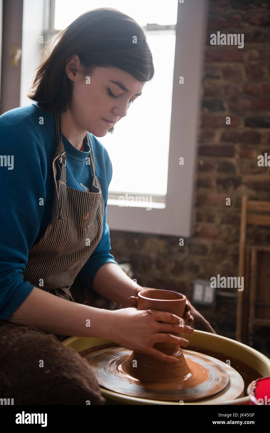 Caucasian woman shaping clay on pottery wheel Stock Photo