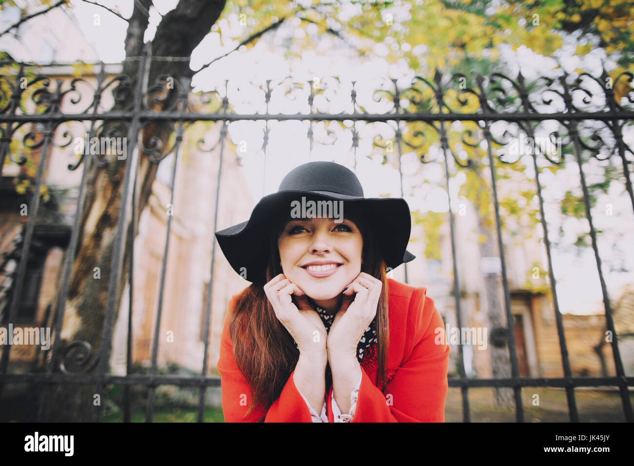 Portrait of smiling Caucasian woman wearing hat near fence Stock Photo