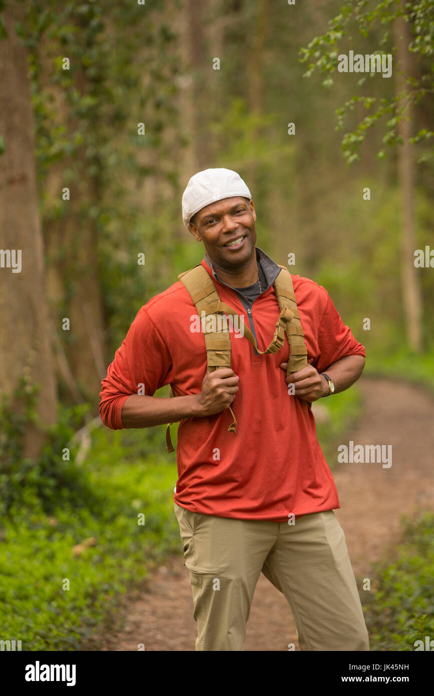 African American man standing on path in forest carrying backpack Stock ...
