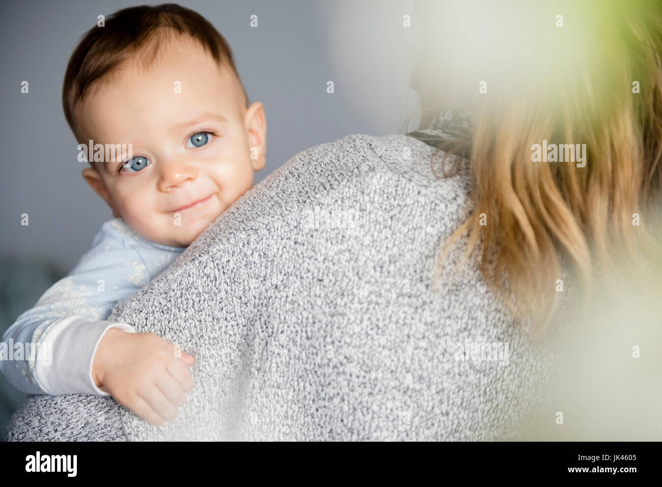 Caucasian baby boy smiling on shoulder of mother Stock Photo