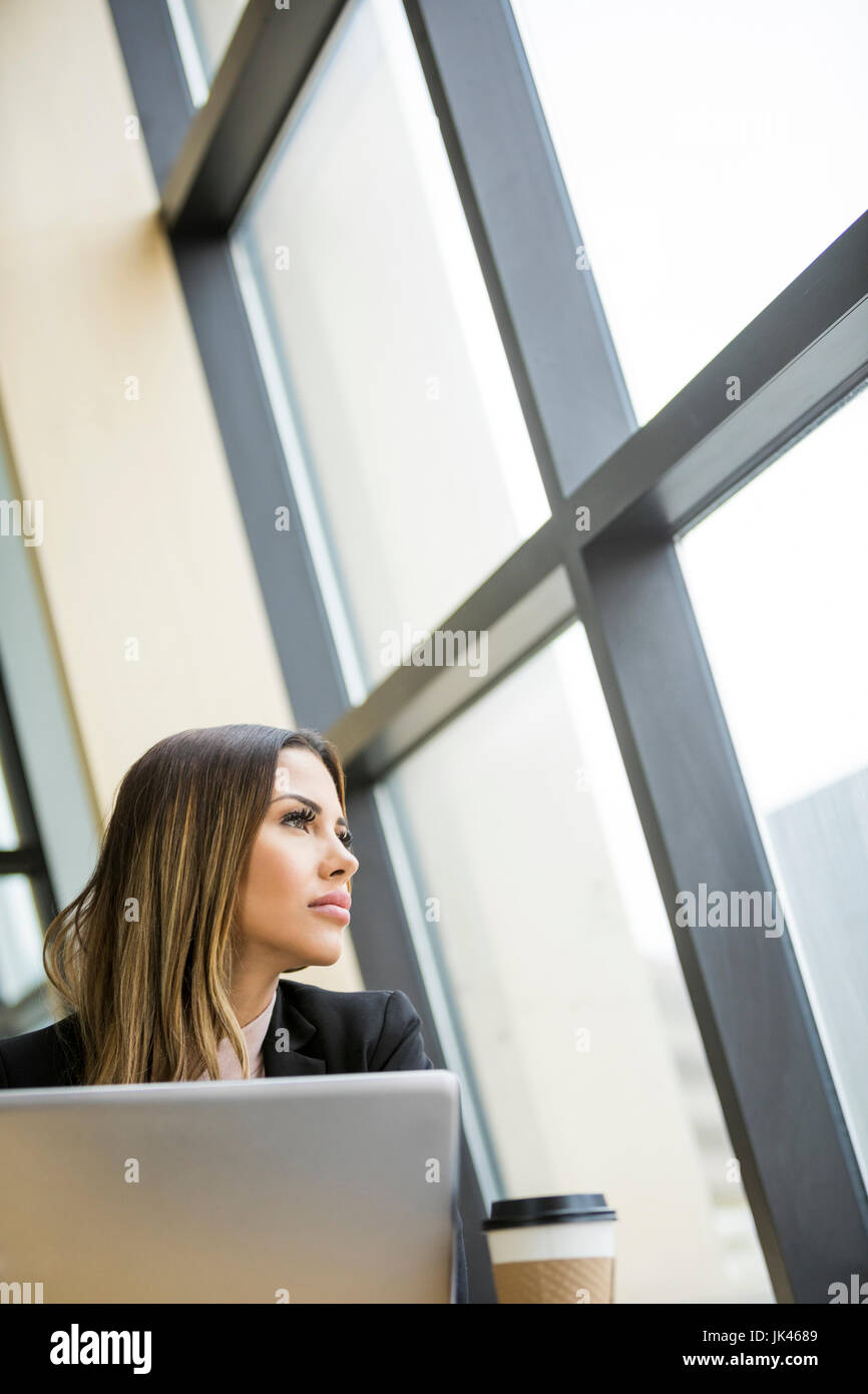 Mixed Race businesswoman with laptop daydreaming Stock Photo