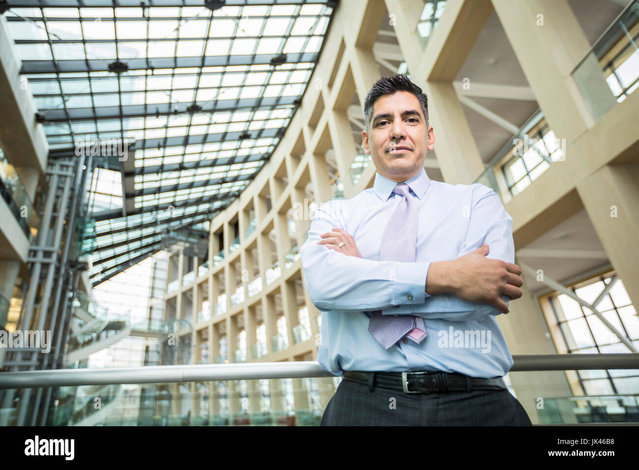 Serious Mixed Race businessman posing in lobby Stock Photo