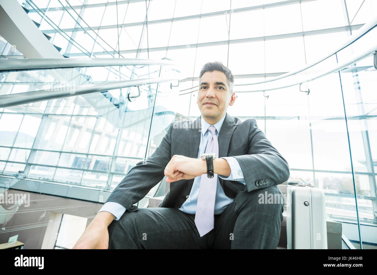 Portrait of smiling Mixed Race businessman sitting on staircase Stock Photo