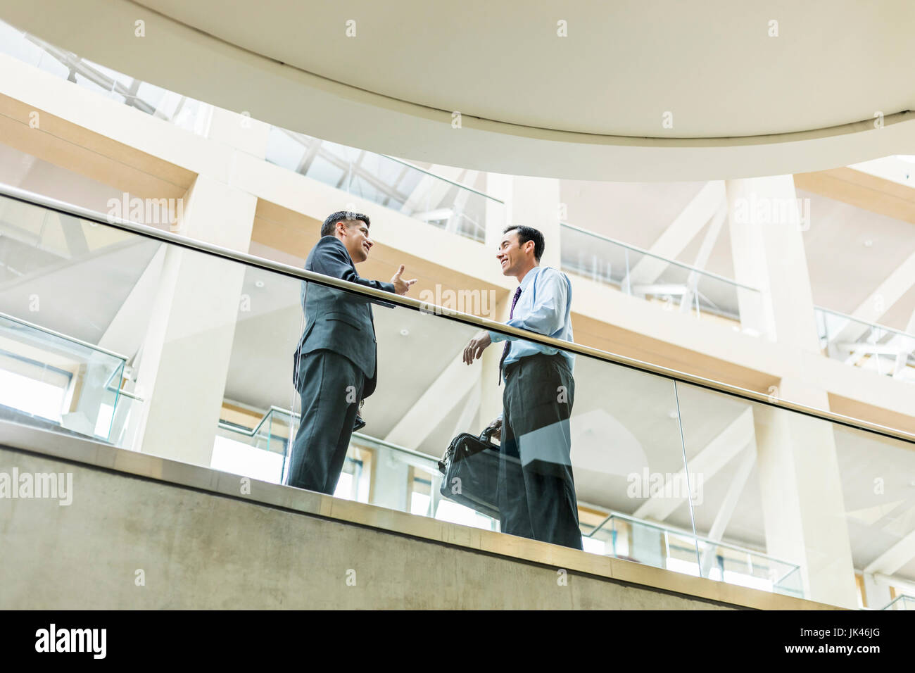 Smiling Mixed Race businessmen talking in lobby Stock Photo