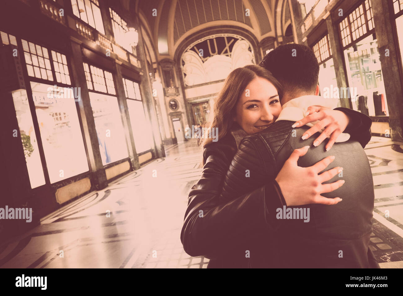 Smiling Caucasian couple hugging in lobby Stock Photo