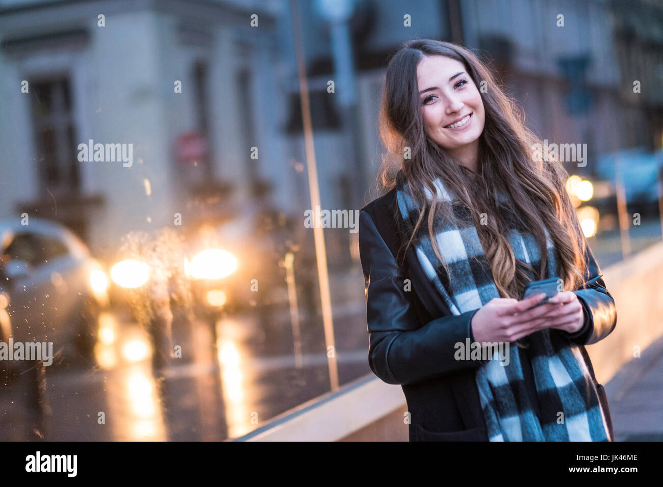 Smiling Caucasian woman texting on cell phone outdoors Stock Photo