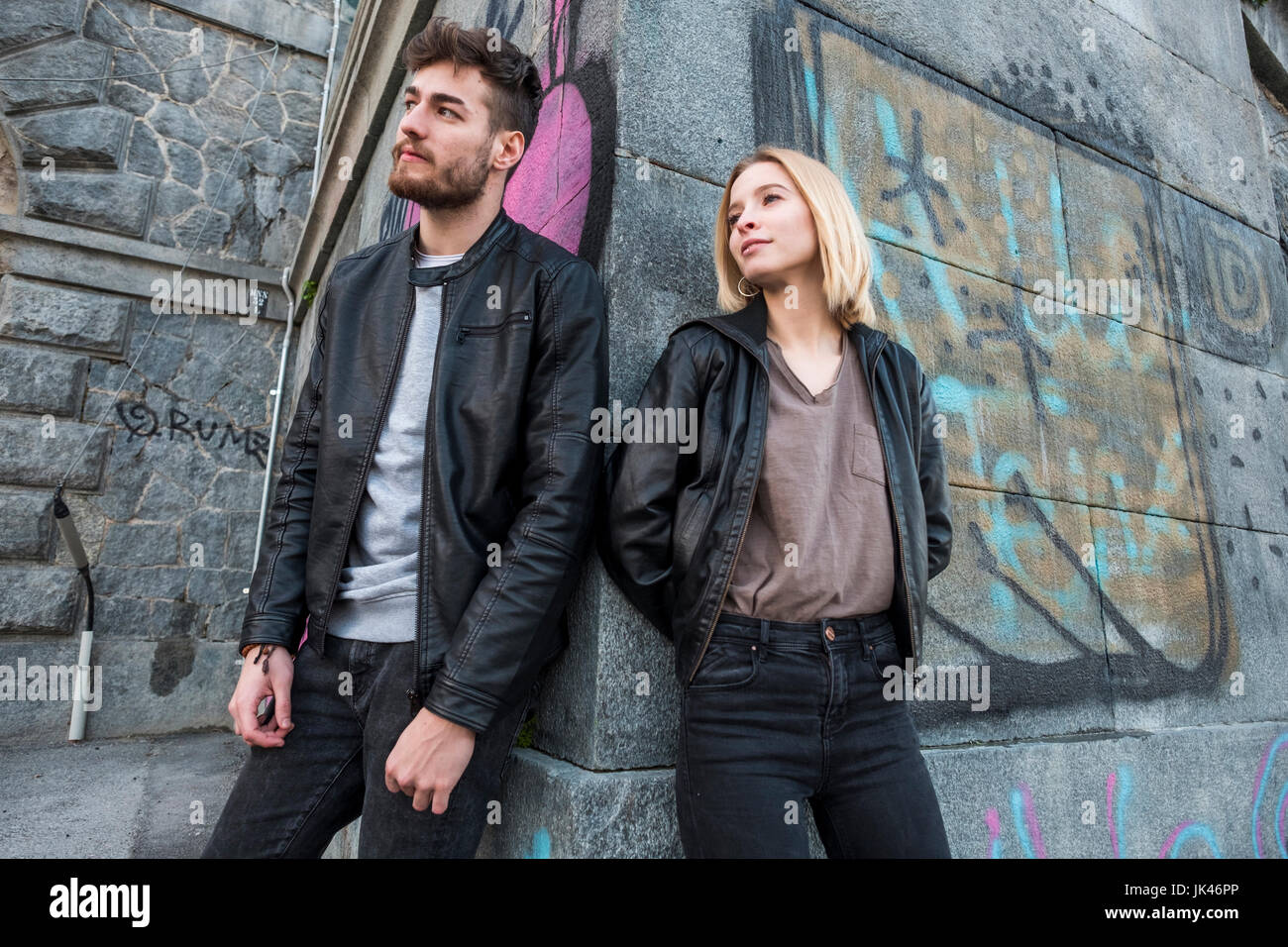 Caucasian couple leaning on wall with graffiti Stock Photo
