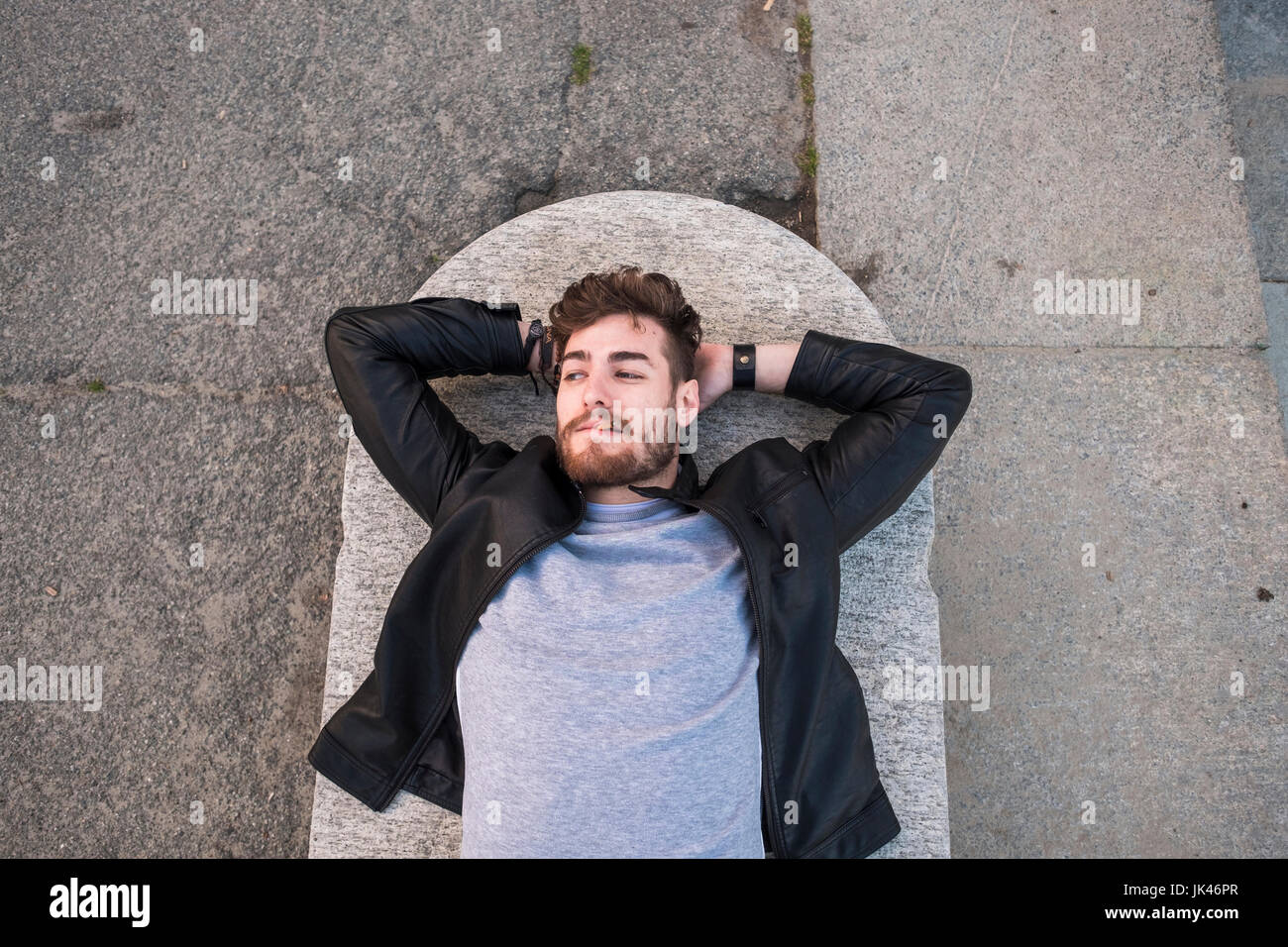 Caucasian man laying on concrete smoking cigarette Stock Photo