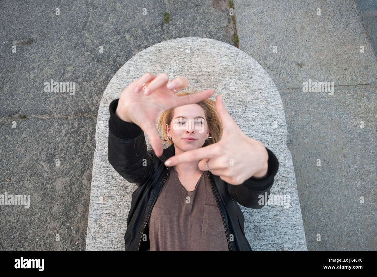 Caucasian woman laying on concrete gesturing square Stock Photo