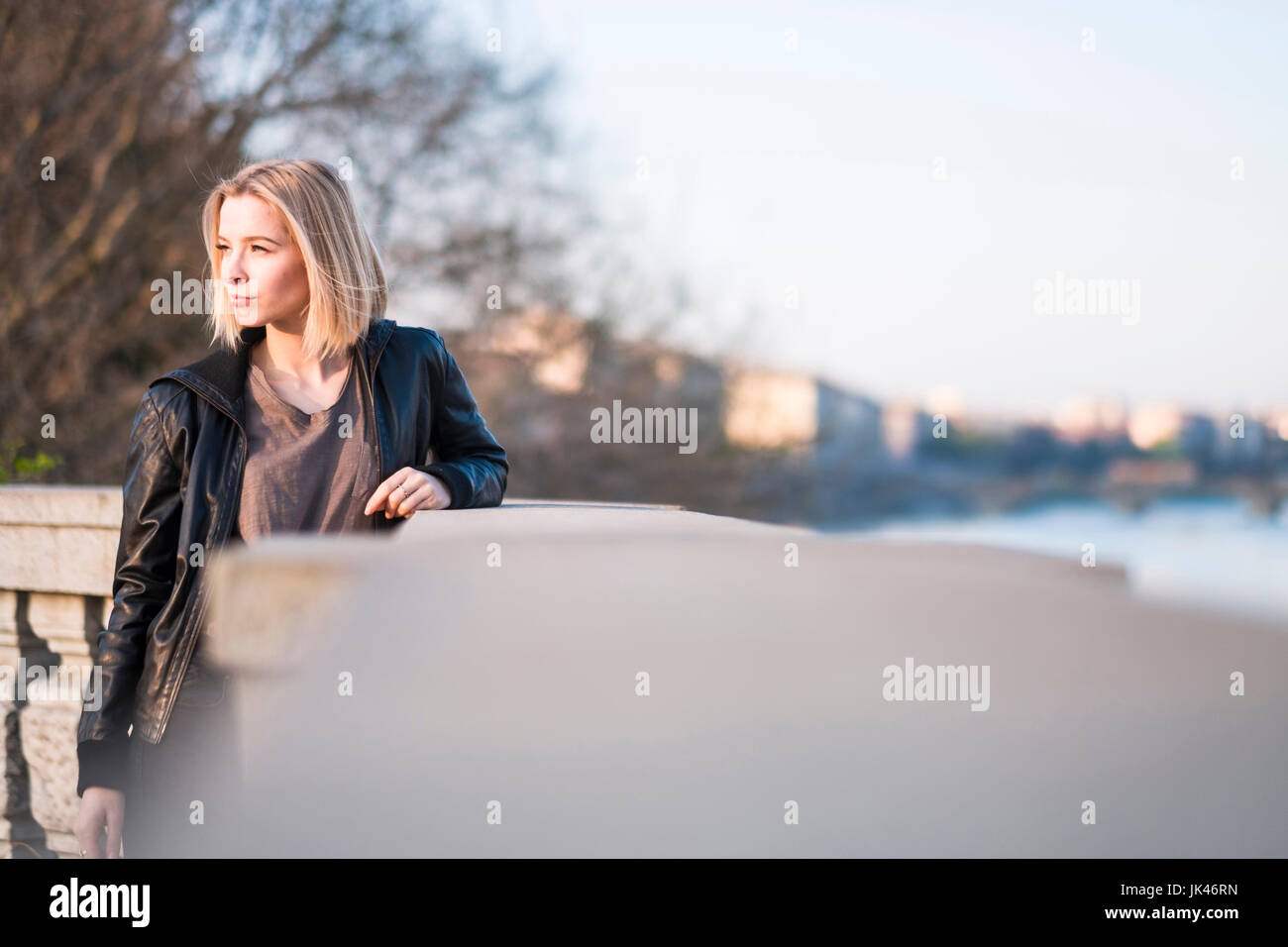 Caucasian woman leaning on wall near river Stock Photo