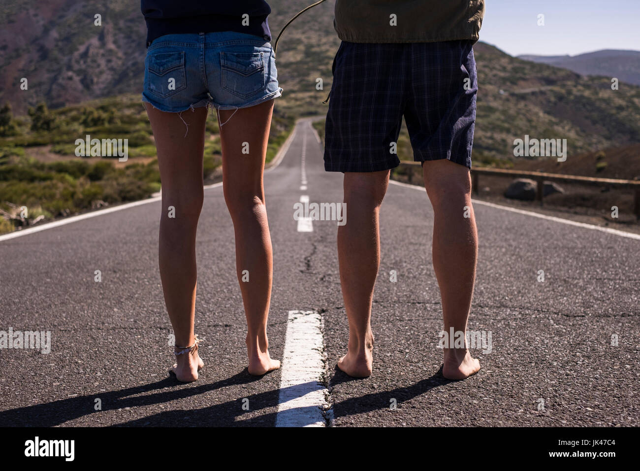 Legs of barefoot Caucasian couple standing in middle of road Stock Photo