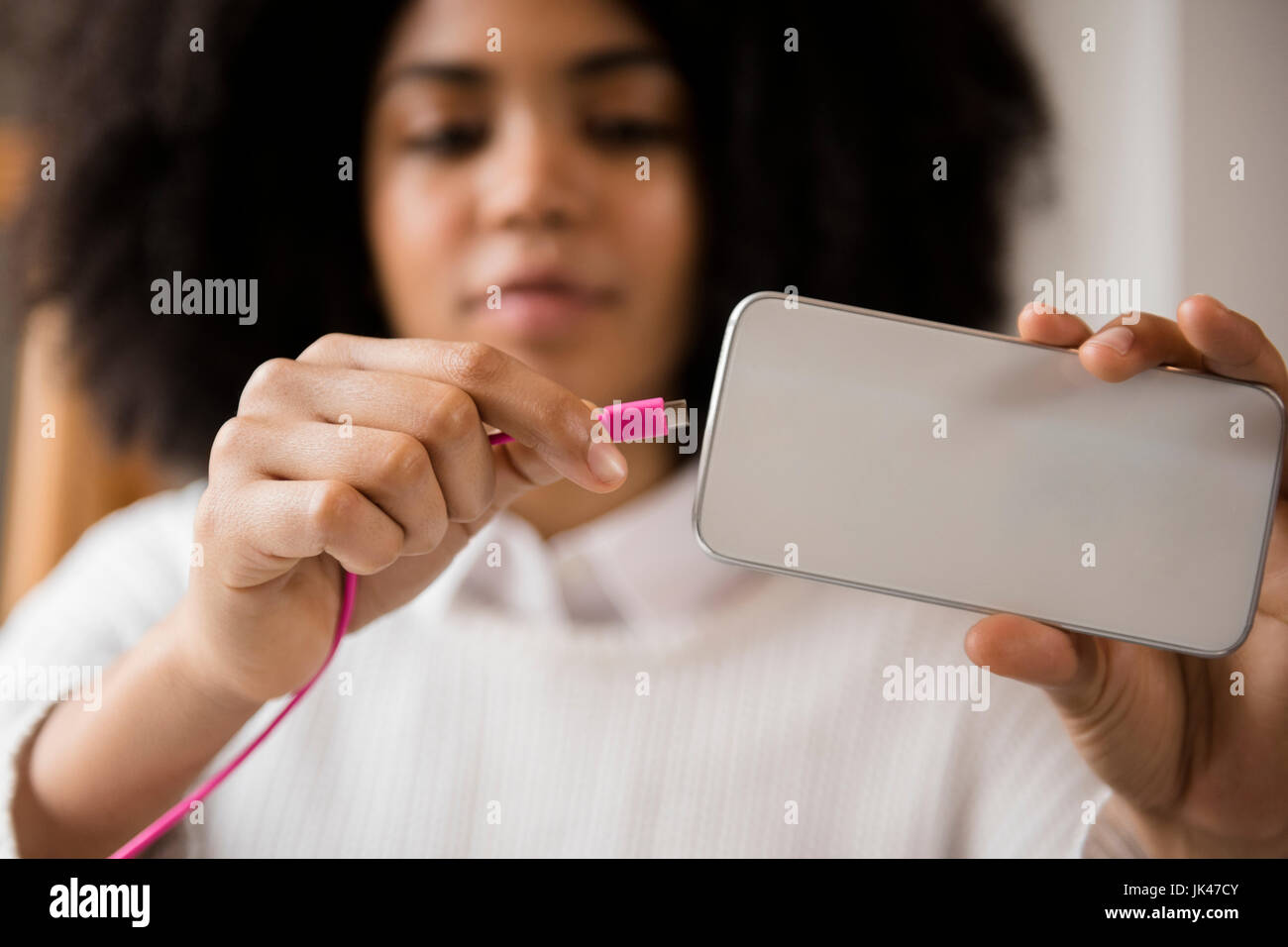 African American woman connecting cable to cell phone Stock Photo