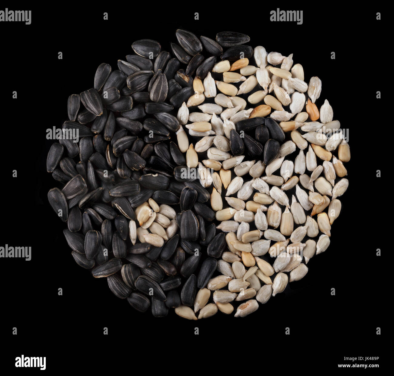 Sunflower seeds on a black background in the form of yin-yang. View ...