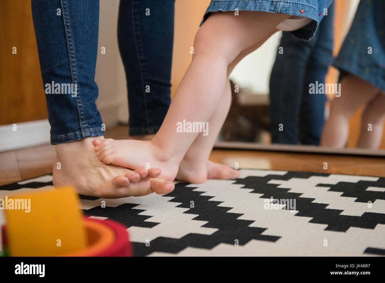 Reflection in mirror of barefoot Caucasian mother and daughter Stock Photo